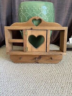 two wooden boxes with hearts in them on the floor next to a green potted plant