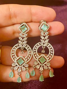 Our Mint CZ Silver finish AD Earrings, the perfect accessory for any Indian outfit or party gown. These earrings have a stunning silver finish, sure to elevate any ensemble. Add a touch of elegance and glamour to your wardrobe with these earrings today. Length - 6 cm Jewellery Care- Keep the jewelry dry, avoid heat and contact with perfumes & water. Jewellery With Gown, Hand Set Hoop Earrings For Party, Hand Set Diamond Drop Earrings For Party, Party Hand Set Diamond Drop Earrings, Elegant Hand Set Dangle Earrings, Party Hand Set Cubic Zirconia Chandelier Earrings, Elegant Dangle Earrings Hand Set, Glamorous Hand Set Drop Earrings, Elegant Dangle Earrings With Hand Set