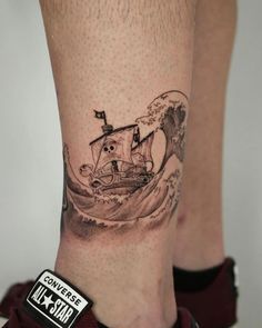 a person with a tattoo on their leg that has a boat in the water and waves