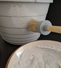 a paintbrush is being used to paint a white bucket with powdered sugar on it