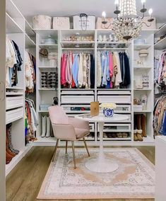 an organized closet with clothes, shoes and chandelier hanging from the ceiling on shelves