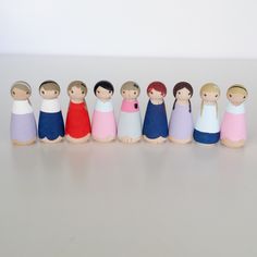 a group of wooden dolls standing next to each other on a white surface with one doll in the middle