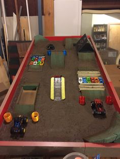 a table that has some cars on it and sand in the middle with other toys