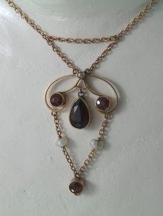 Simply gorgeous genuine antique edwardian necklaceset in solid 9ct rose gold necklacewith a drop pendant laviere style necklacewith genuine and natural garnet gemstonesalso genuine seed pearlsthis gorgeous pendant also has a chain at the topsits beautifully on the necklacethe chain stabilises the pendant and holds in placeat hte base of the pendant there is a loopi think there may have been something else attached herethe lobster clasp is not original to the piecethe piece is stamped 9kthe chain Antique Oval Pearl Pendant Jewelry, Antique Bronze Gemstone Jewelry, Victorian Bronze Round Necklace, Victorian Round Bronze Necklace, Bronze Round Victorian Necklace, Antique Teardrop Yellow Gold Necklaces, Antique Yellow Gold Teardrop Necklace, Antique Yellow Gold Teardrop Necklaces, Vintage Gold Drop Necklace