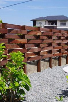 a wooden fence is shown in front of a house with gravel and rocks on the ground