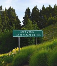 a road sign that says don't worry god is always on time with trees in the background