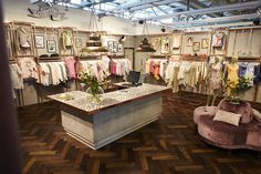 a clothing store with clothes hanging on racks and chairs in front of the display counter