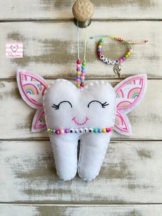 a tooth shaped ornament hanging on a wooden wall with beads and beaded necklaces