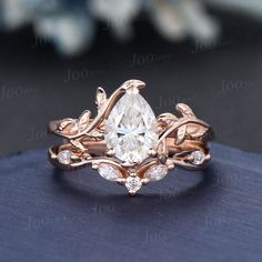 an engagement ring with a pear shaped diamond in the center and leaves on each side