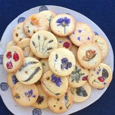 a white plate topped with cookies covered in frosting and dried flowers on top of it