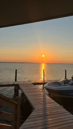 the sun is setting over the water and boats are parked on the dock at the end of the pier