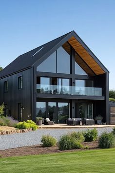 a large black house sitting on top of a lush green field