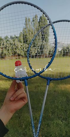 two tennis racquets are held up in the air by someone's hand