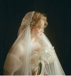 a woman wearing a veil and holding flowers