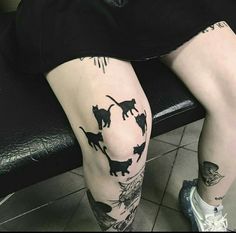 a person sitting on a bench with tattoos on their legs and leggings that have cats drawn on them