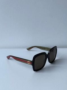 Nuevas gafas de sol negras Gucci GG0036SN 002.

 Con patas brillantes con rayas Gucci verdes/rojas y logotipos de metal dorado en las patillas.

 Lentes de color marrón oscuro 100% con protección UV.

 Forma cuadrada clásica para cualquier tamaño o forma de rostro.

 Súper ligero y perfecto para el uso diario.

 Viene con estuche, bolsa de satén a juego, tela y toda la documentación.

 Talla 54-22-140.

 100% auténtico y sin uso.

 Precio de venta al público $400. Gucci Green Polarized Sunglasses, Gucci Green Sunglasses With Mirrored Lenses, Gucci Green Sunglasses With Uv Protection, Luxury Green Gucci Sunglasses, Gucci Casual Green Sunglasses, Casual Green Gucci Sunglasses, Gucci Red Sunglasses With Uv Protection, Red Gucci Sunglasses With Uv Protection, Gucci Multicolor Sunglasses