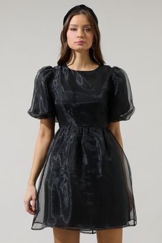 If you like to be trendy, you need Borza Organza Mini Dress! It’s such an adorable dress that has angled, ruffled short sleeves. The back side has an invisible zipper closure followed by a big bow tie back detail. Bodice has a relaxed fit and has a flowy skirt with an organza fabric all over this dress. It will look cuter with heels and your favorite jewelry pieces. - Lined- Puffed short sleeves- Bow details- Zipper back- Comes in 2 colorsSize + Fit - Model is 5'10" and wearing size XS- Measurem Black A-line Puff Sleeve Dress For Formal Occasions, Black A-line Puff Sleeve Evening Dress, Chic A-line Puff Sleeve Party Dress, Chic Black A-line Puff Sleeve Dress, Black Fitted Midi Dress With Bow, Puff Sleeve Mini Dress With Bow For Party, Puff Sleeve Dress With Bow For Party, Black A-line Puff Sleeve Dress For Evening, Elegant Short Sleeve Dress With Ruffles