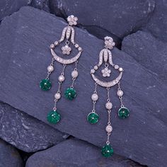 These dazzling chandelier earrings are each accented with three (3) carved emerald flower dangles and forty-four (44) round brilliant cut diamonds that are prong and bezel set. The earrings measure 75.1mm long by 21.0mm wide and they are finished with friction backs for pierced ears. Luxury Emerald Earrings With Diamond Accents, Luxury Green Chandelier Earrings, Green Diamond Chandelier Drop Earrings, Luxury Green Dangle Chandelier Earrings, Luxury Green Bridal Earrings, Elegant Green Earrings With Rose Cut Diamonds, Carved Emerald, Diamond Chandelier Earrings, Diamond Chandelier