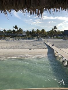 people are walking on the beach and in the water near a pier that extends into the ocean