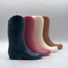 four pairs of cowboy boots sitting next to each other on a white surface with candles in the middle