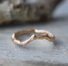 a close up of a gold ring on a wooden surface with a rock in the background