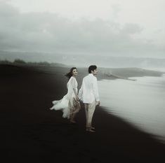 a man and woman are walking on the beach