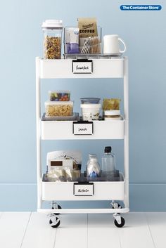 a white cart filled with lots of food on top of a blue wall next to a floor