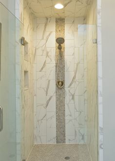 a walk in shower sitting next to a white tiled wall and floor covered in marble