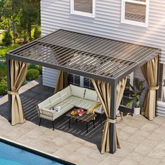 an outdoor living area with patio furniture and curtains on the side of a house next to a swimming pool