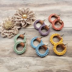 four pairs of crochet hoop earrings on wooden table with flower in the background