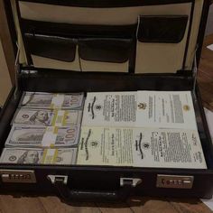 an open briefcase filled with money sitting on top of a wooden floor