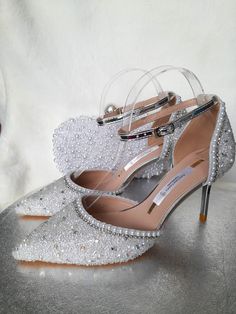 a pair of silver high heeled shoes sitting on top of a table