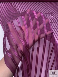 a woman's hand is holding onto a purple sheer material with lines on it