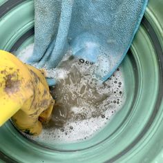 a blue towel is in a green bowl with some water and soap on the rim