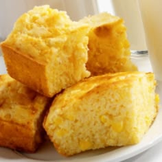 several pieces of cornbread on a plate next to a glass of milk