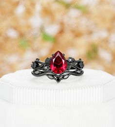 This black gold ruby ring is a stunning and enchanting piece that captures attention with its fusion of dark elegance and fiery passion. Crafted from Silver/10k/14k/18k white gold, plated with black rhodium, the ring creates a dramatic backdrop for the ruby centerpiece. The deep red ruby gemstone radiates with intensity and symbolizes love and strength. As the light catches the ruby, it illuminates the black gold band, creating a mesmerizing contrast. With its unique color combination and exquis Black Ruby Jewelry For Wedding, Black Ruby Anniversary Ring, Wedding Black Ruby Jewelry, Black Ruby Ring For Anniversary, Round Black Ruby Ring, Formal Black Rings With Ruby, Black Ruby Wedding Jewelry, Black And Red Promise Ring, Black Ruby Rings As Gift