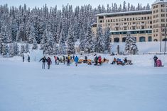 many people are standing in the snow near a building and trees with snow on them