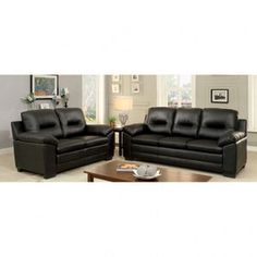 two black leather sofas sitting next to each other in front of a coffee table