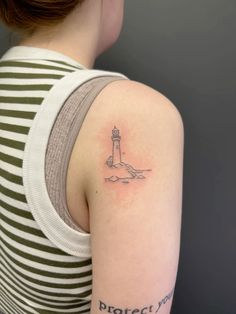 a woman with a small lighthouse tattoo on her back shoulder and arm is looking at the camera