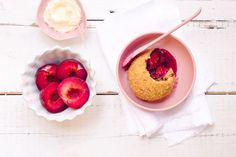 a bowl of ice cream next to a plate of fresh fruit on a white wooden table