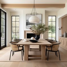 a dining room table with chairs and a vase filled with flowers on top of it