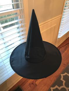 a black witches hat sitting on top of a wooden floor next to a window with blinds