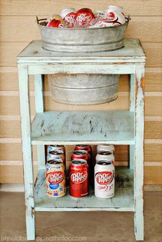 an old ice bucket with soda cans in it on a shelf next to a wall