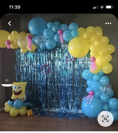 balloons and streamers are hanging from the ceiling near a spongebob balloon arch