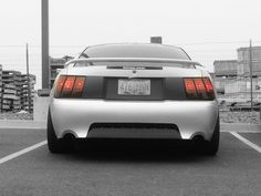 the back end of a white car parked in a parking lot