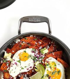 two fried eggs on top of sweet potato wedges in a skillet with salsa