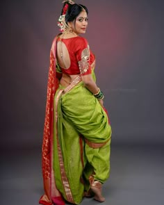 a woman in a green and red sari is posing for the camera with her hands on her hips