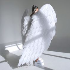 an angel with white wings is standing in the sun and casting a shadow on the floor