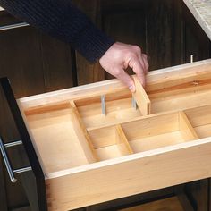 a person holding a knife in a drawer with other drawers on the counter behind them