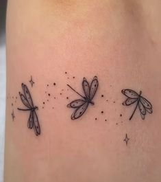 three small dragonflies on the side of a woman's right thigh, with stars around them